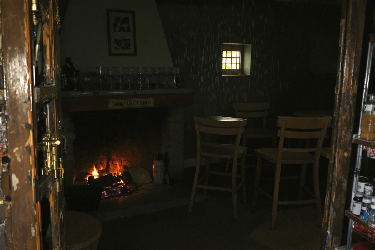 The dim interior of a small rural Irish bar with a peat fire and empty wooden stools